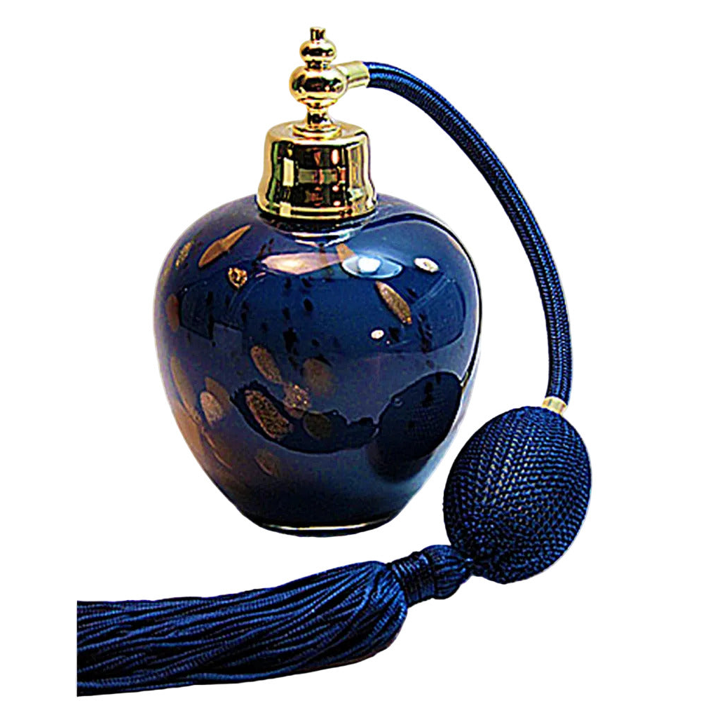 A glossy dark blue glass perfume bottle with gold leaf accents, a gold-toned metal atomizer cap, and a long dark blue fabric neck and tassel, shown on a plain white background.