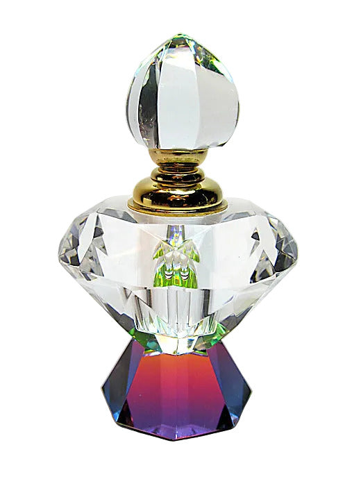 A clear faceted crystal perfume bottle with a gold-toned neck and a colorful iridescent purple-pink base, photographed on a light gray background.