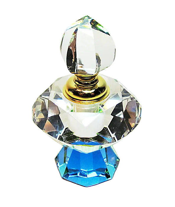 A faceted crystal perfume bottle with a clear glass stopper, a gold collar, and a bright blue geometric base on a white background.