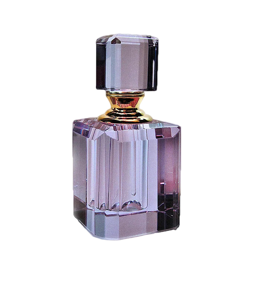 A faceted glass perfume bottle with a purple tint, a gold neck collar, and a matching purple cap, shown on a white background.